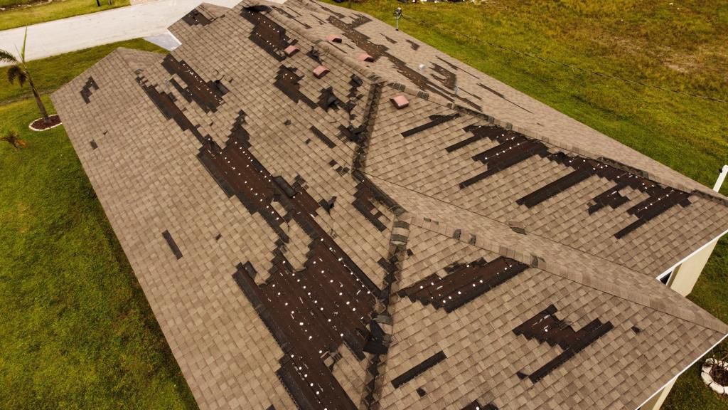 Aerial close-up of a roof section showing a pattern of storm-damaged and missing shingles